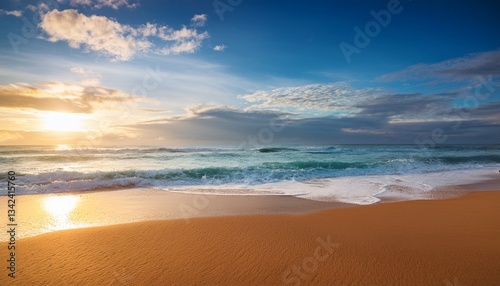 sandy beach blue cloudy sky and soft ocean wave with warm sunset light