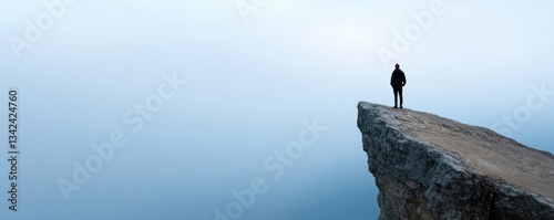 Solitary figure on cliff edge overlooking vast horizon in minimalist landscape