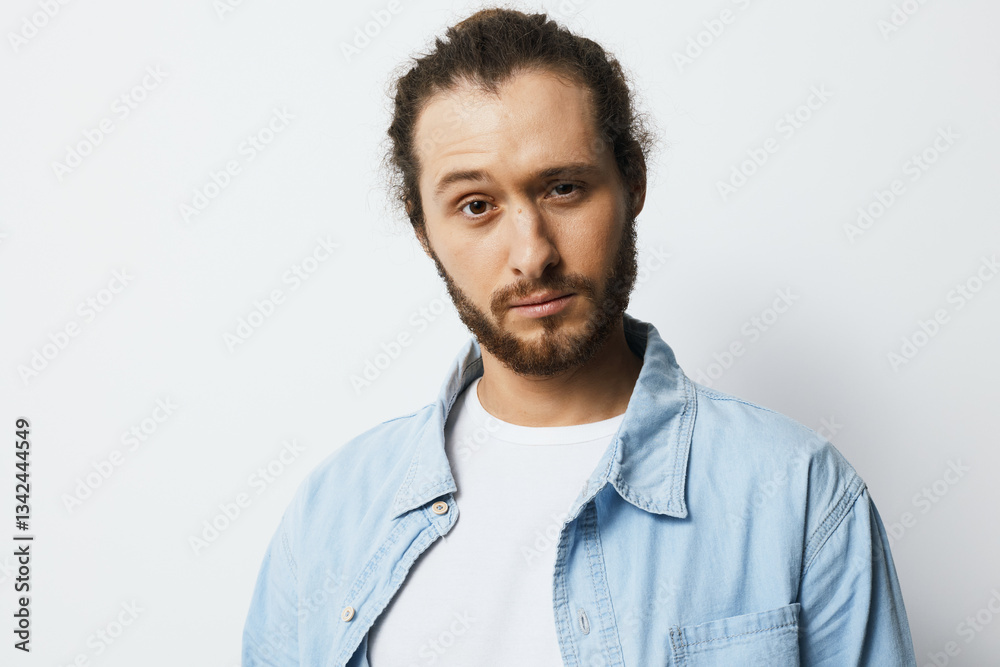 Confident young man with a beard wearing a blue shirt against a light background, conveying self assurance and style in a modern setting Confident young man with a beard wearing a blue shirt against a light background, conveying self assurance and style in a modern setting