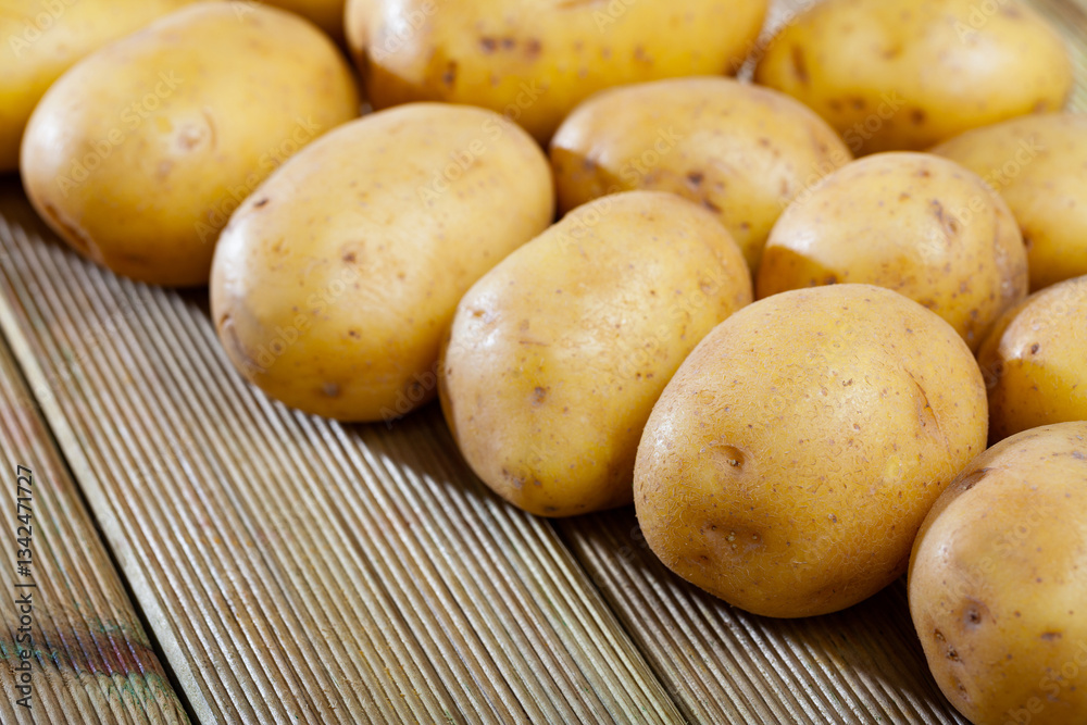 Image of raw fresh young potatoes at wooden table in home kitchen, nobody.. Image of raw fresh young potatoes at wooden table in home kitchen, nobody..