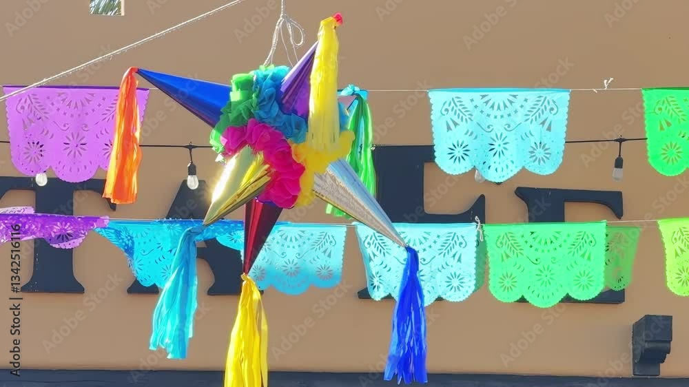 A colorful star-shaped piñata hangs among vibrant papel picado banners, creating a festive atmosphere under string lights outdoors.