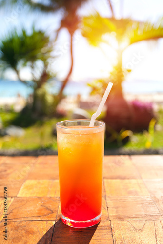 Fototapeta Naklejka Na Ścianę i Meble -  Orange Fruit shake cocktail with ice and straw in it, tropical vacation. Summer holidays