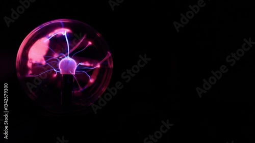 A Plasma Ball Set to the Left With a Hand Touching the Backside of the Glass Ball