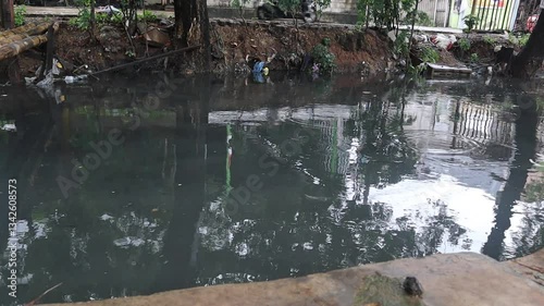 Black polluted water canal stream begins to overflow, close up view.