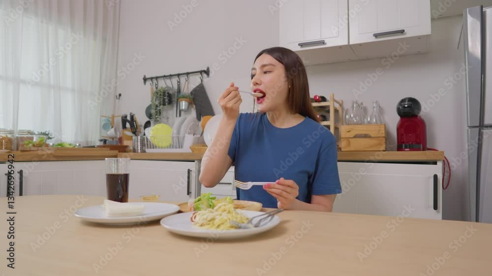 Asian attractive female eating green salad and spaghetti in kitchen room. Asian attractive female eating green salad and spaghetti in kitchen room.