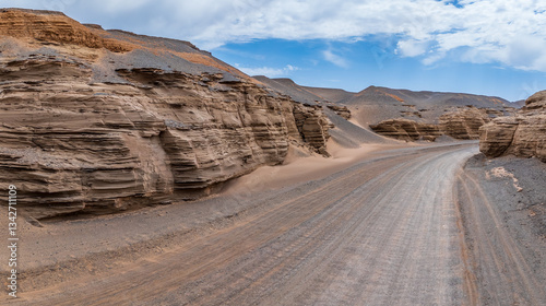 Canvas Print Sand road leads through desert canyon under blue sky
