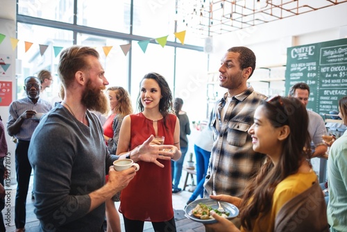 Foto Group of diverse people socializing at a casual gathering, enjoying drinks and snacks, engaging in lively conversation in a bright, modern setting