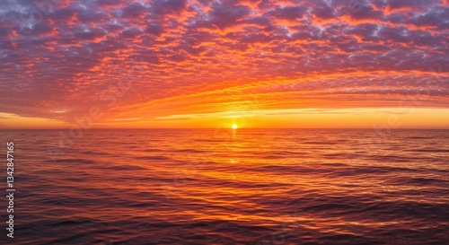 Sunset over calm ocean waters with colorful clouds reflecting light
