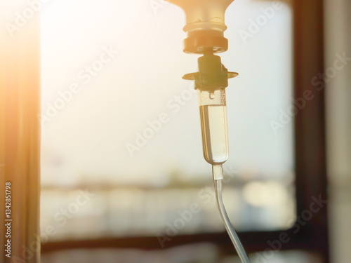 Intravenous drip with liquid medicine in a hospital room. Close-up of IV infusion system with sunlight and blurred background. Healthcare, treatment, and recovery concept.