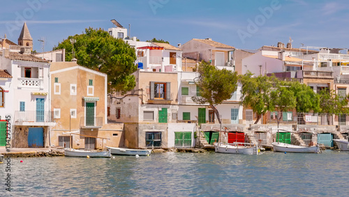 long shot of fishing boats and houses at the harbor of portocolom on mallorca, spain
