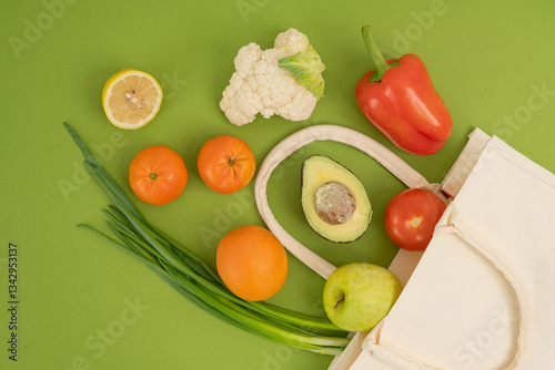 Flat lay composition with fresh fruits and vegetables in eco bag on green background