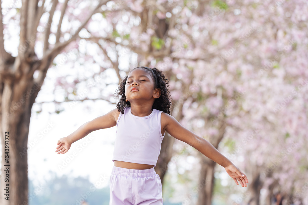 A young girl stands with arms outstretched, eyes closed, embracing the fresh air under pink cherry blossoms. She radiates a sense of freedom, peace, and joy, fully immersed in the beauty of nature. A young girl stands with arms outstretched, eyes closed, embracing the fresh air under pink cherry blossoms. She radiates a sense of freedom, peace, and joy, fully immersed in the beauty of nature.