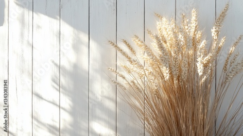 A golden halo of wheat ears, kissed by the sun, stood proudly against a pristine, white wooden backdrop, evoking images of rustic charm and the bounty of harvest.