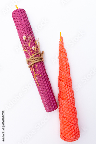 twisted candles made from natural wax by hand on a background of white boards. Paper packaging and sheets of honeycomb. Decoration of dried flowers of clover. Rustic Style.