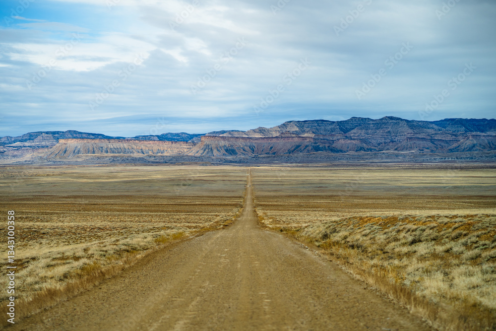 Remote Desert Road Leading to Utah Badlands Under Overcast Sky - Remote Desert Road Leading to Utah Badlands Under Overcast Sky -