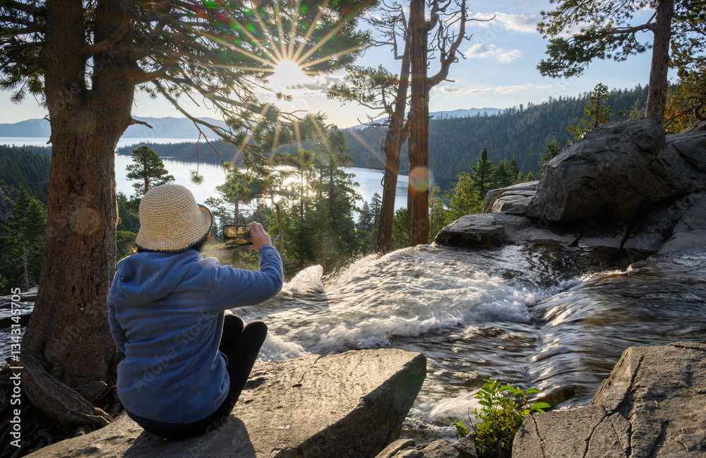 Woman taking photos of Lower Eagle Falls using smartphone at sunrise. Emerald Bay. South Lake Tahoe. California.