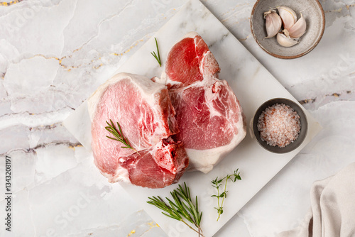 Two raw pork fillets on a bone on a white marble table