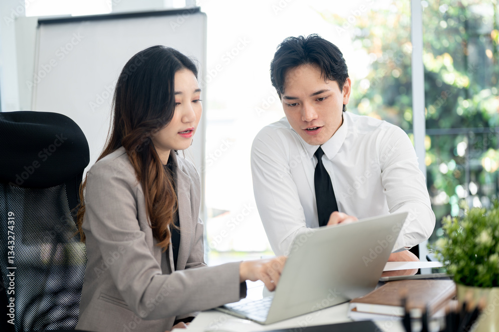 Female office worker is pointing and explaining the business data on laptop to her male coworker. Female office worker is pointing and explaining the business data on laptop to her male coworker.