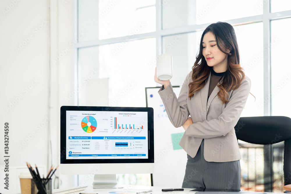 Businesswoman or female office worker holding mug standing next to monitor showing charts and data. Businesswoman or female office worker holding mug standing next to monitor showing charts and data.