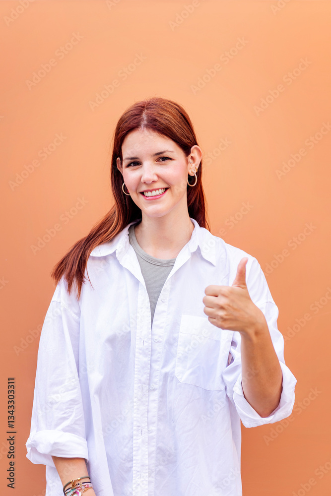 young woman giving a thumb up gesture while smiling looking at camera in a positive and friendly mood suggesting that she is happy and content, copyspace for text young woman giving a thumb up gesture while smiling looking at camera in a positive and friendly mood suggesting that she is happy and content, copyspace for text