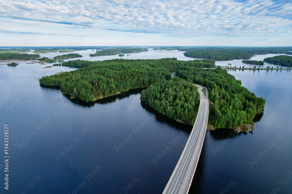 Fototapeta premium A scenic aerial view of Luukkaansalmi Bridge in Lappeenranta, Finland, crossing the blue waters of Lake Saimaa. The lush green islands and calm summer atmosphere create a breathtaking landscape.