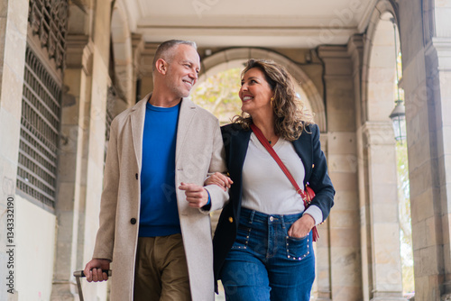 Cheerful couple enjoying a leisurely stroll together while holding hands, radiating happiness and affection in a charming urban environment, sharing a good moments together