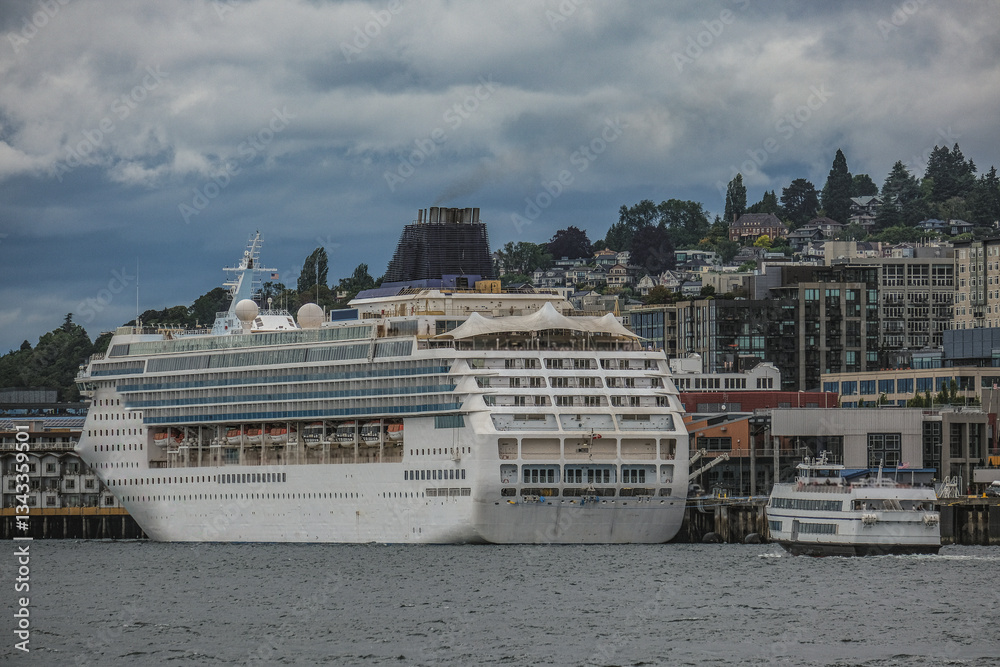 Modern cruiseship cruise ship ocean liner Sun sail away departure from Seattle, Washington State for Alaska summer cruising on grey cloudy day with city skyline