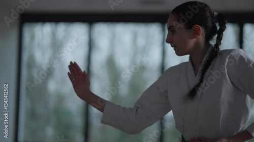 Woman training Karate in the dark, with big windows in the back