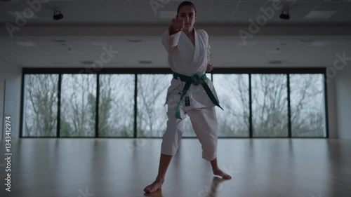 Woman training Karate in the dark, with big windows in the back