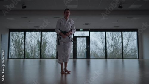 Woman training Karate in the dark, with big windows in the back