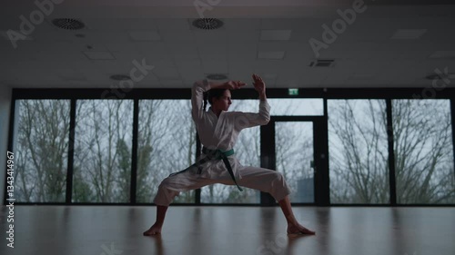 Woman training Karate in the dark, with big windows in the back
