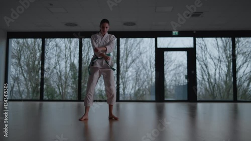 Woman training Karate in the dark, with big windows in the back