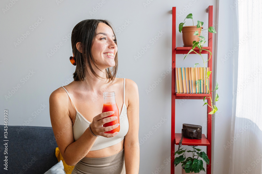 Healthy millennial young woman enjoying homemade smoothie fruit drink at home after workout exercise routine.