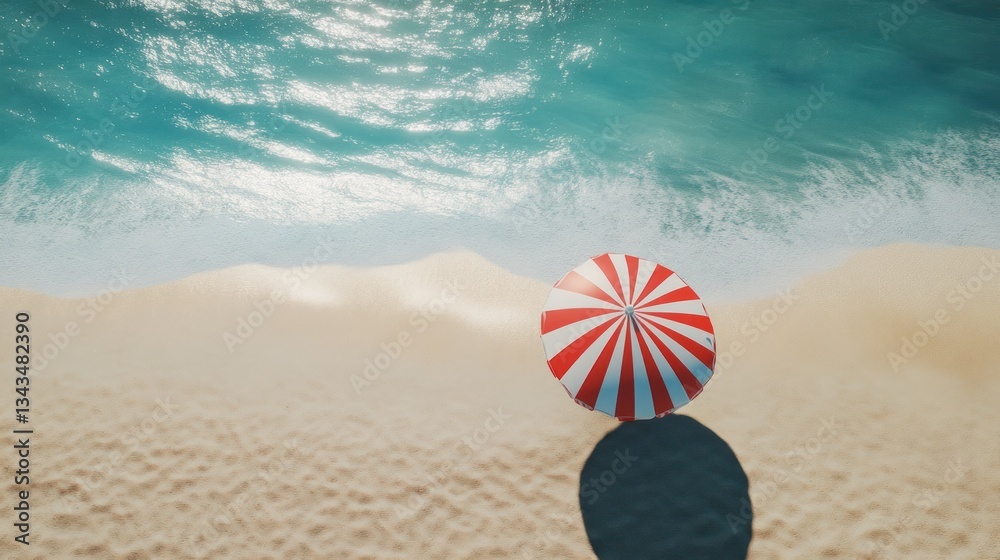 Obraz premium Overhead view of red and white striped beach umbrella on sandy beach near ocean.