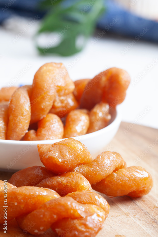 A close up of a plate of traditional South African Koeksisters with a wooden table underneath