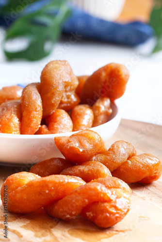 A close up of a plate of traditional South African Koeksisters with a wooden table underneath
