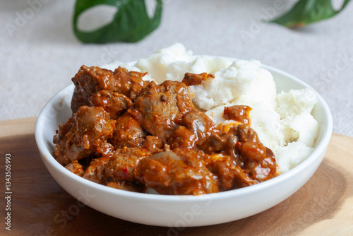 A bowl of South African street food, spicy chicken livers with traditional pap
