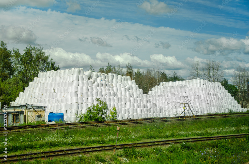 Fototapeta premium Stacks of White Bags Against a Blue Sky in a Rural Scene