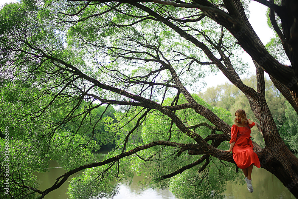 Fototapeta premium springtime dreaming female girl sitting on a tree branch, spring forest park