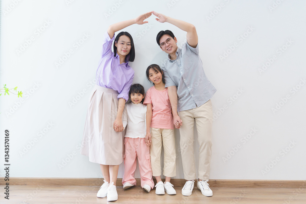 Happy family creating a heart shape with hands in a minimalistic indoor space during a sunny day Happy family creating a heart shape with hands in a minimalistic indoor space during a sunny day