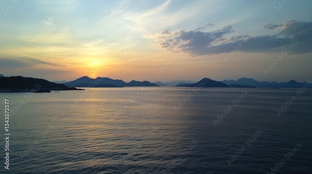 Panoramic seascape at dusk, sun sinking over island silhouettes with rippled water Panoramic seascape at dusk, sun sinking over island silhouettes with rippled water