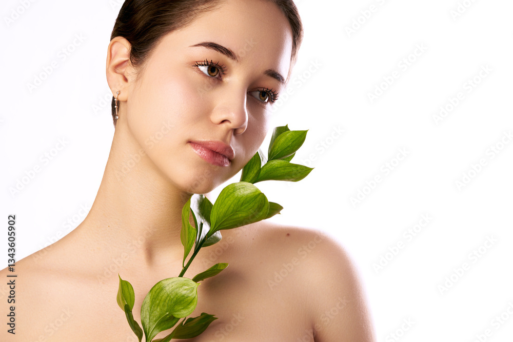 A young woman with a serene expression, natural makeup, and elegant earrings, holding a green plant against her bare shoulder, symbolizing beauty and nature. A young woman with a serene expression, natural makeup, and elegant earrings, holding a green plant against her bare shoulder, symbolizing beauty and nature.