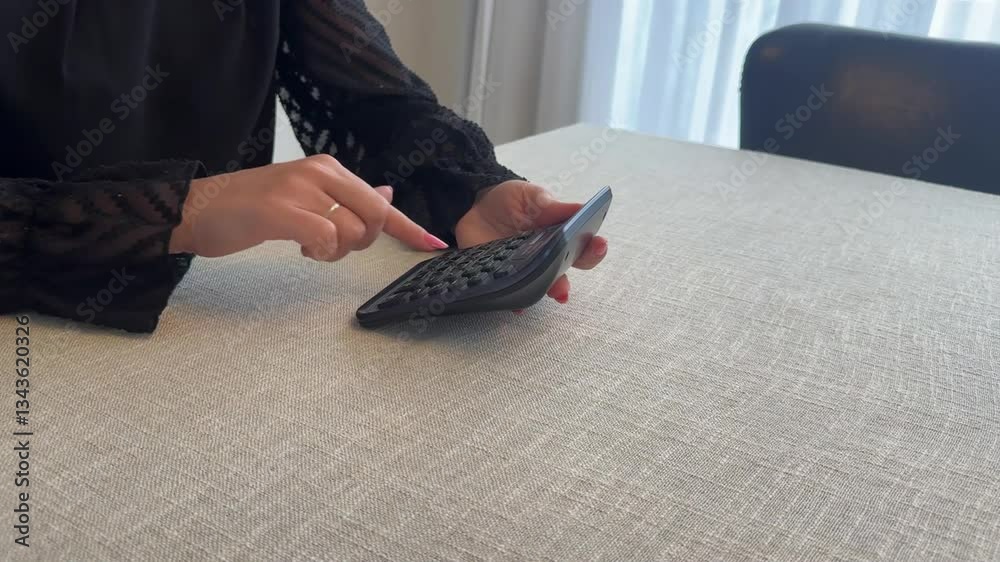 Mulher faz calculos em calculadora em casa 