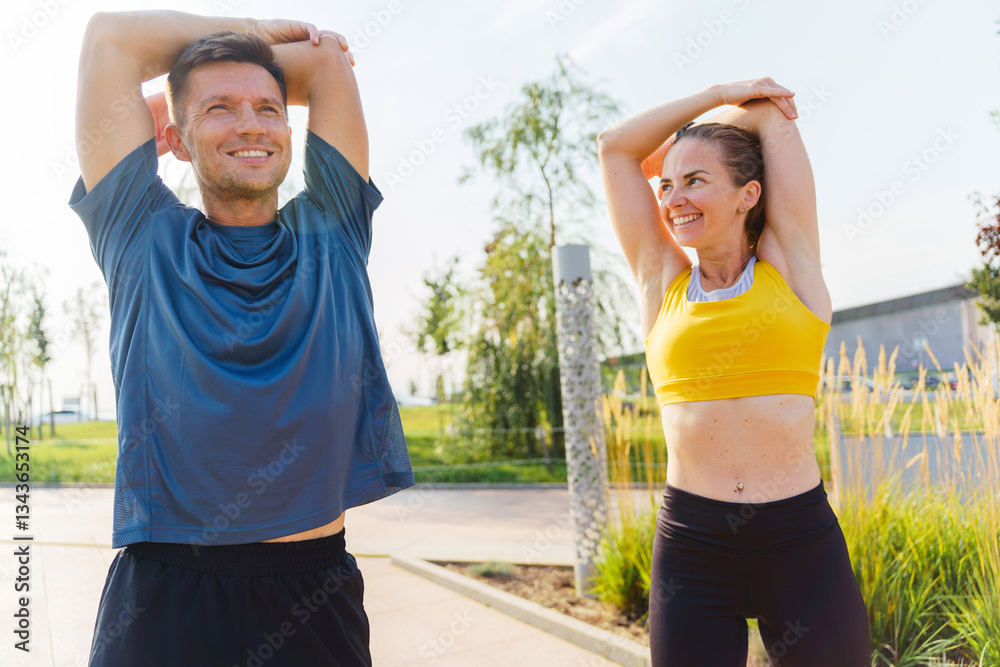 Obraz premium Couple enjoying stretching exercises in a sunny park during a morning workout session