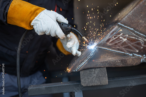Welder joining metal parts with welding torch creating sparks