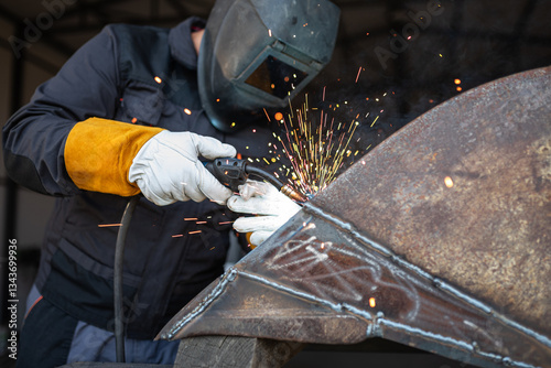 Professional welder joining metal parts using mig mag technique in workshop