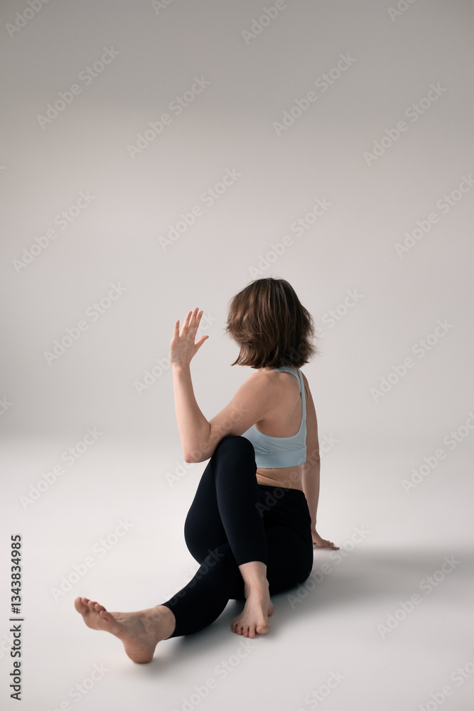 Woman practicing yoga or stretching exercise, performing a seated twist pose for flexibility and relaxation Woman practicing yoga or stretching exercise, performing a seated twist pose for flexibility and relaxation