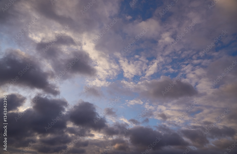 Fototapeta premium Soft clouds illuminated by the pink light of the sun create a gentle warm hue against the blue sky. Symbolizes harmony and tranquility.