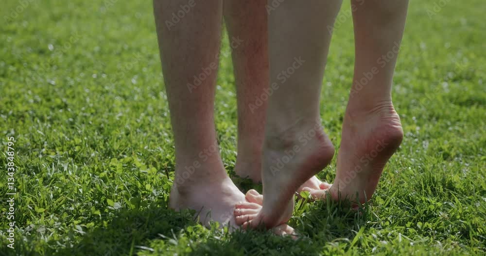 Romantic shot, close-up of the legs of a couple in love barefoot. Women's feet stand on men's feet on the green grass during a romantic kiss on a sunny summer day. High quality 4k footage Romantic shot, close-up of the legs of a couple in love barefoot. Women's feet stand on men's feet on the green grass during a romantic kiss on a sunny summer day. High quality 4k footage