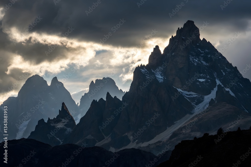 Fototapeta premium Majestic Mountain Peaks Under Dramatic Cloudy Sky at Dusk